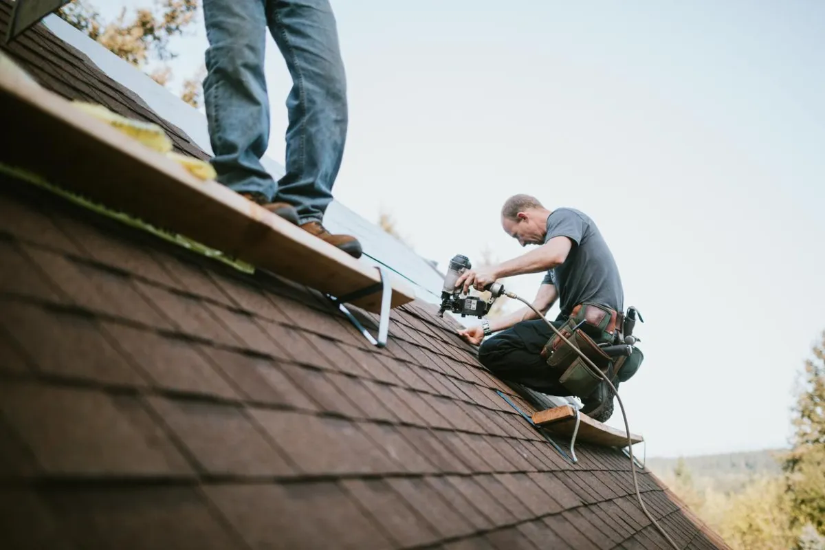 Professional roofers performing commercial roofing installation on a sloped roof using safety equipment